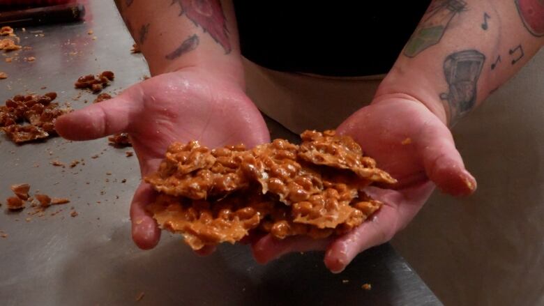 Two hands hold out peanut brittle