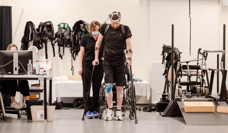 Man walking with a walker and headgear. 