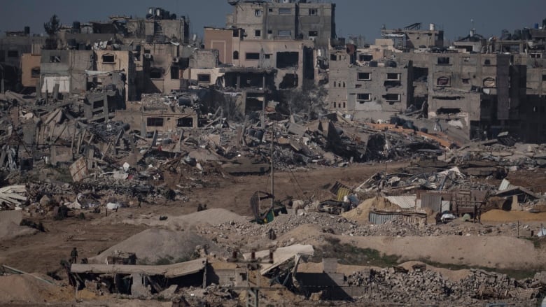 Soldiers walk through a bombed out wasteland.