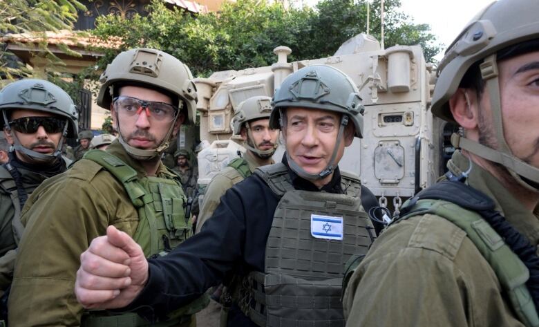 Israeli Prime Minister Benjamin Netanyahu, centre, wears a protective vest and helmet.