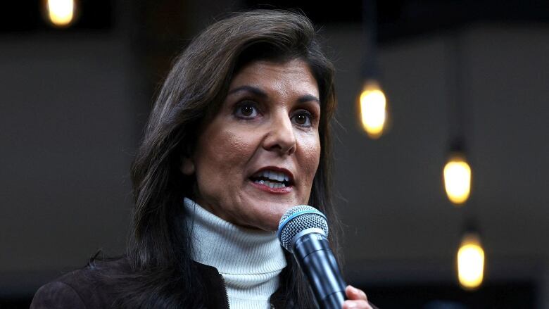 A woman speaks into a microphone at a political event.