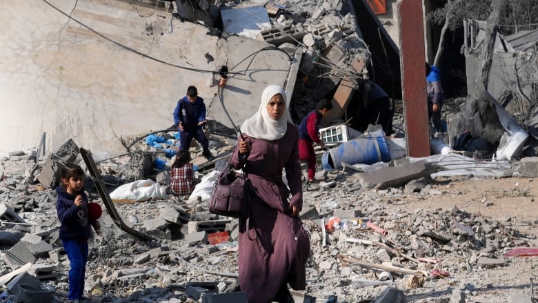 A woman and three children walk past the rubble of a building in the Gaza Strip.