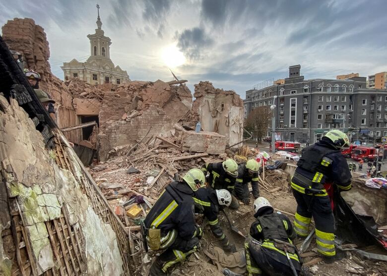 Firefighters work to free a person trapped under the rubble of a damaged building.