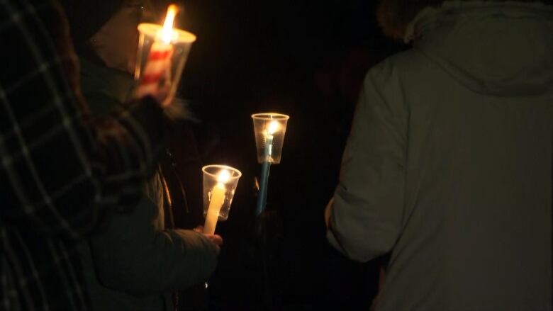 People hold candles in the dark.