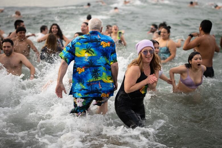 Dozens of people smile and yell as they splash around in waist-deep water.