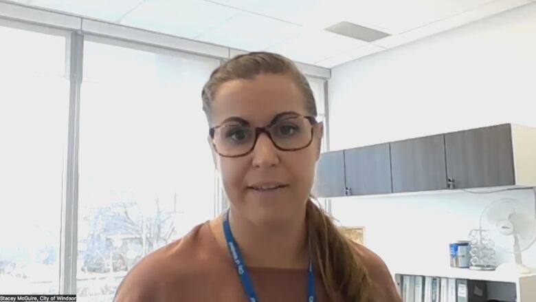 A woman wearing glasses in an office setting.