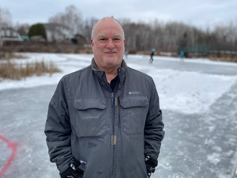 A man standing outside in front of a frozen pond.