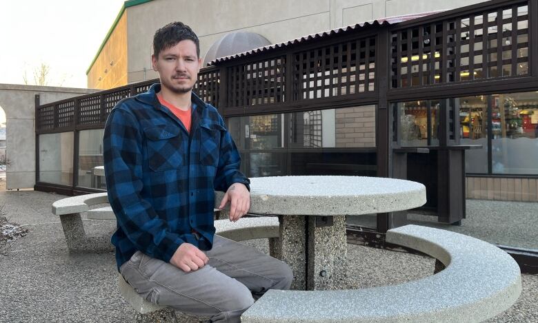 A man sits at a pinic table.