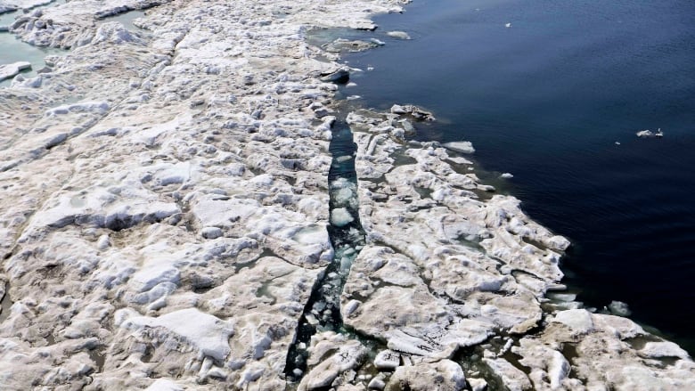 An ice-breaking ship is seen from above, moving through  sea ice.