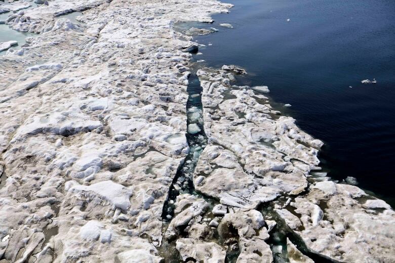 An ice-breaking ship is seen from above, moving through  sea ice.