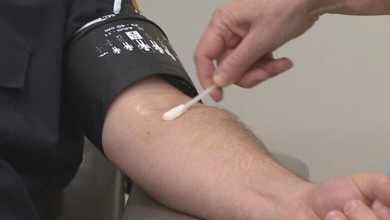 Close-up of a man's arm being prepared for a blood donation.