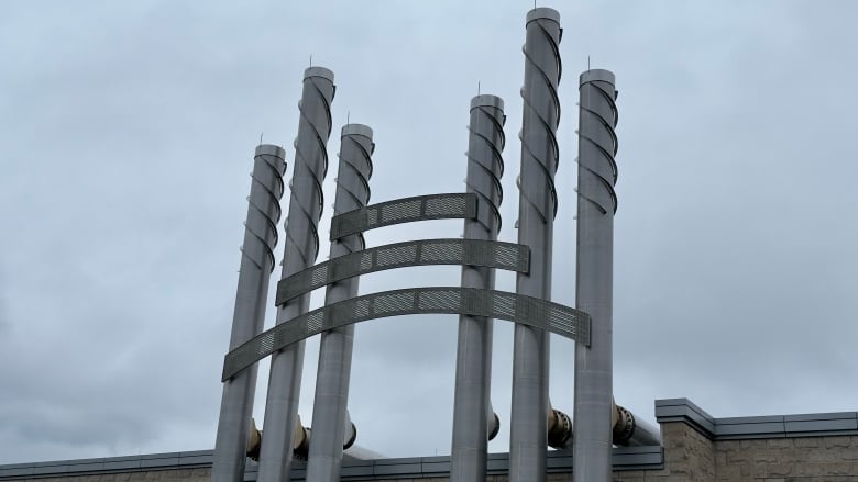 Skinny metal piping shaped into an H sits atop a building.