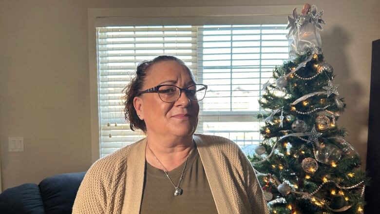 A woman standing next to a christmas tree.