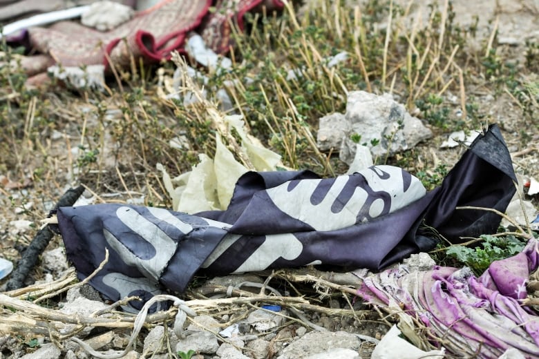 A black and white flag lies tattered on the ground.