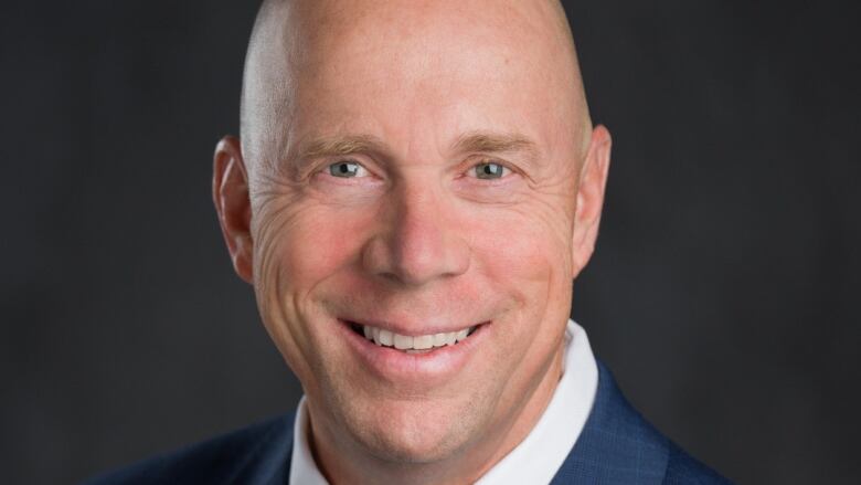 Ron Cannan is shown in a headshot. He is a bald white man wearing a blue suit and tie.