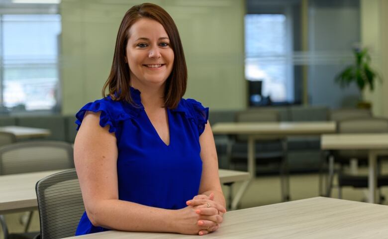 Robyn Romano wears a blue blouse as she sits at a table and looks directly into the camera.