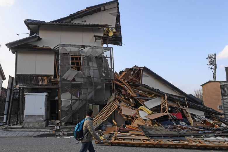 A man walks past quake-collapsed buildings in Wajima, Japan.