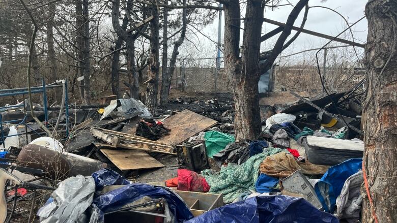 Tents, plywood and blankets lay scattered across the ground. 