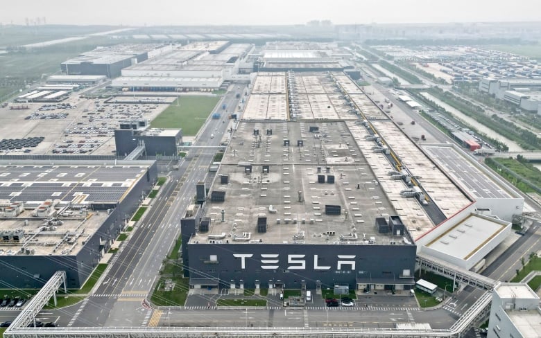 An aerial view of a large building with a huge sign reading 'Tesla.'