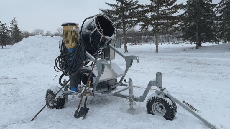 A snow-making machine sits in a snowy field.