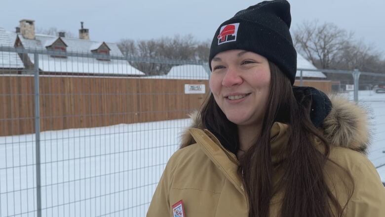 A woman in a black toque stands outside.