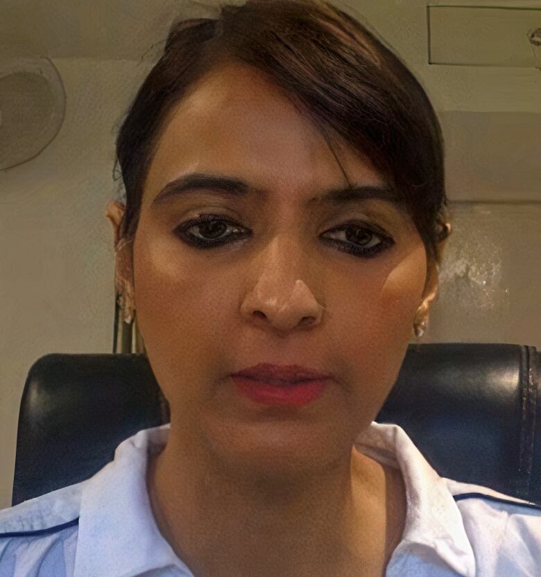 A close-up shot of a woman in a white shirt sporting eye makeup and bright lipstick.