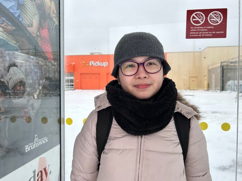 A grinning woman wearing a hat, jacket, backpack and scarf