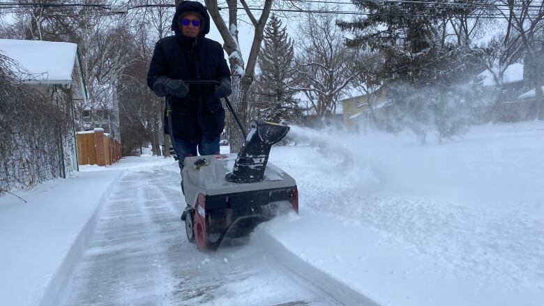 A man clearing the sidewalk of snow in Saskatoon after 15 cm fell over night.