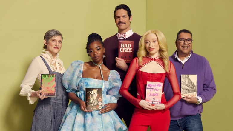 People pose with books, a white woman in overalls, a Black woman in a dress, a Cree man, a Black woman with albinism, a brown man in purple.