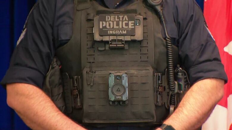 A police officer wears a tactical vest with a black body camera attached.