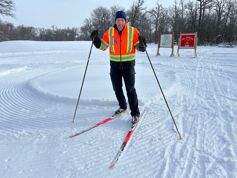 A man smiles and poses wearing cross-country skis.