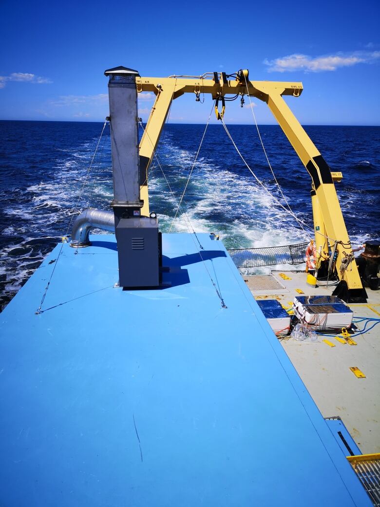 The deck of a ship at sea with a yellow crane