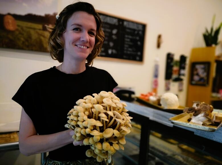 A woman holds a bouquet of wild enoki mushrooms.