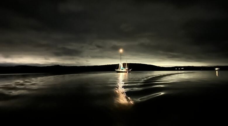 A sailboat lit up at night, including a bright star on the top of the mast. 