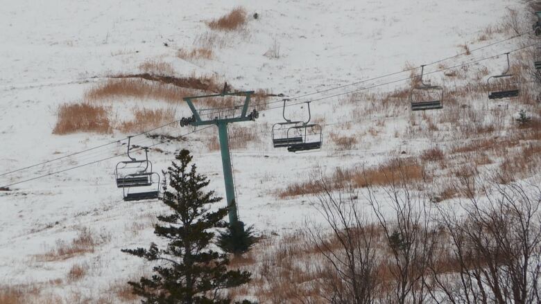 A ski lift runs up a grassy hill.