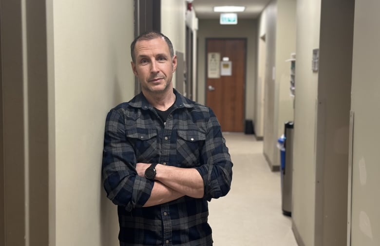 Man stands in hallway with arms crossed