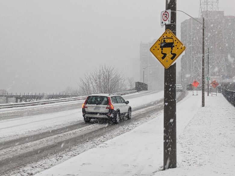 A snowy road with a car is shown, along with a sign indicating that the bridge could be slippery.