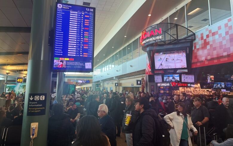 A large crowd of people fills an airport.