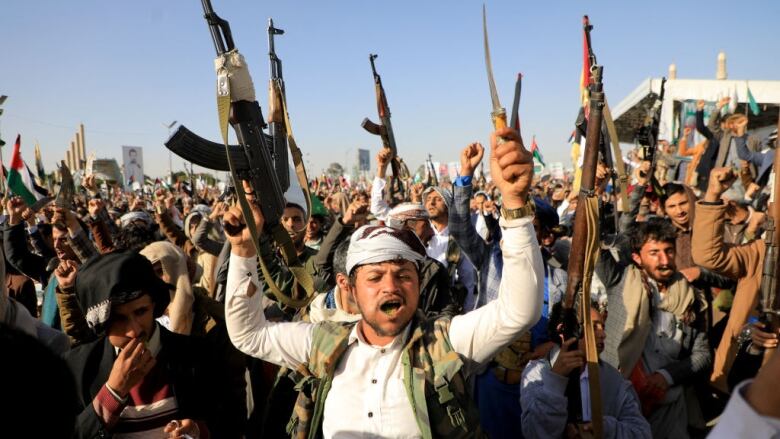 Men hold weapons in the air during a protest.