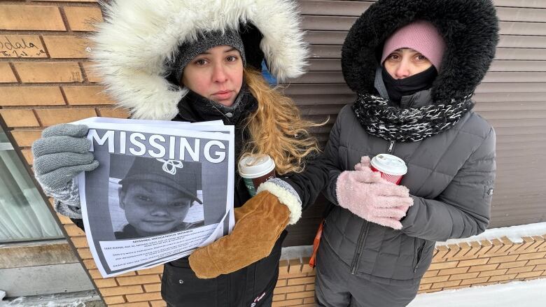 A woman holds up a missing person poster. 