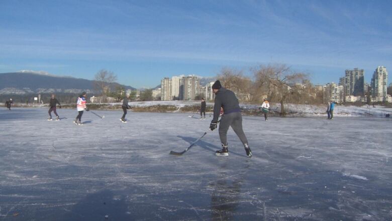 People are seen skating on a frozen pond with the mountains and ocean in the background. 