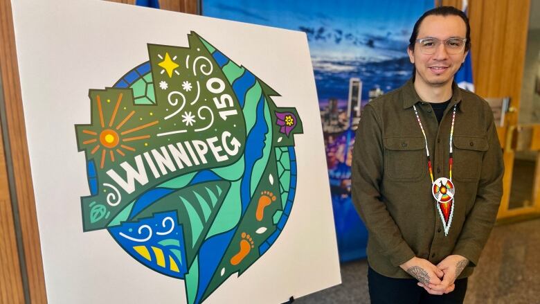 A man stands by an easel with the Winnipeg 150 logo.