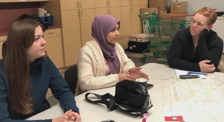 Three women are seen sitting next to each other in this candid photo from an informal class.