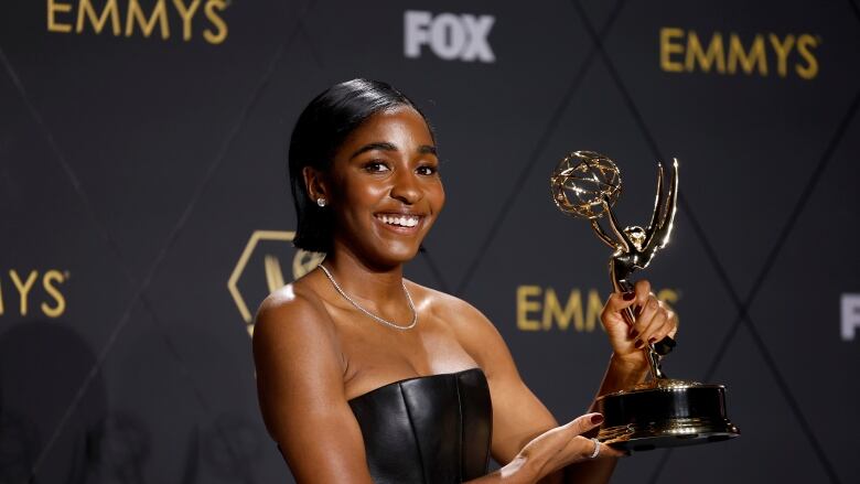 Woman in black dress holds award show