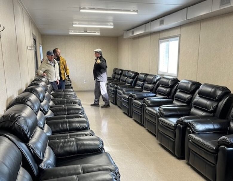 A row of black reclining chairs in a trailer.