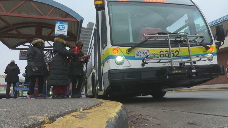 People in winter clothing line up for a bus.