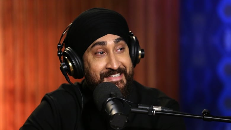 Jasmeet Raina, a Punjabi Sikh man wearing a black turban, seated in front of a studio microphone.