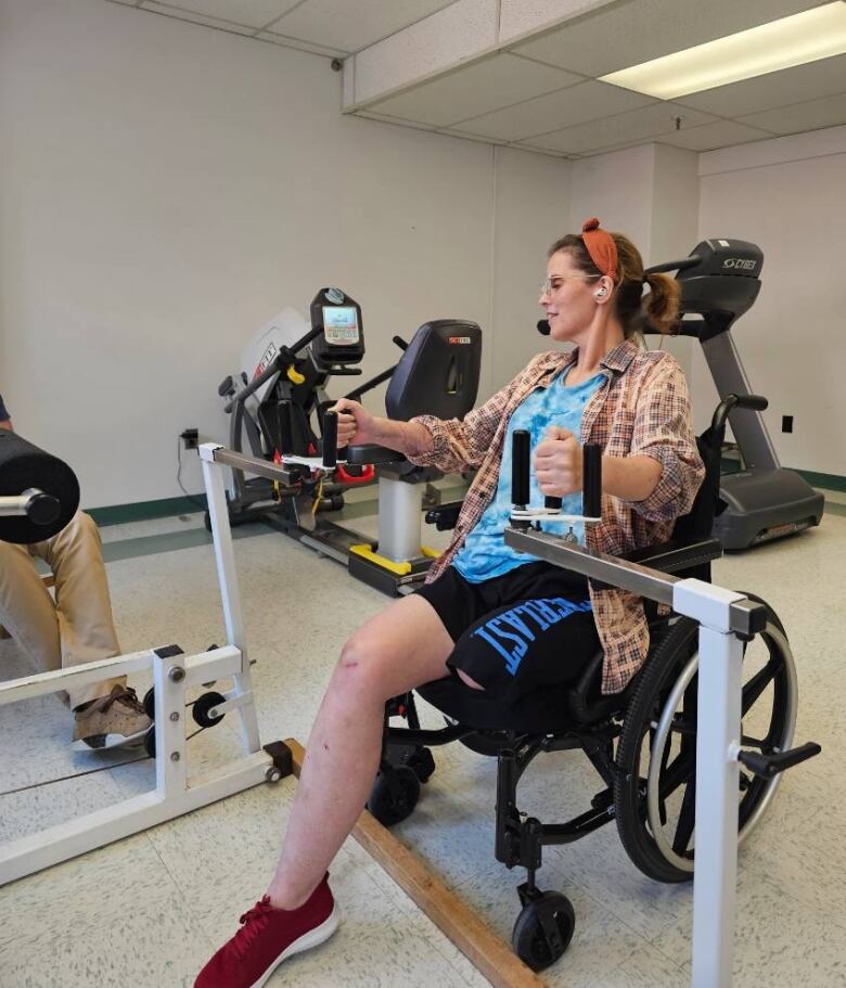 A woman in a wheelchair using physiotherapy equipment. 