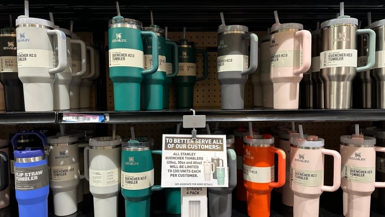 Different coloured reusable tumblers site on a shelves in a store.