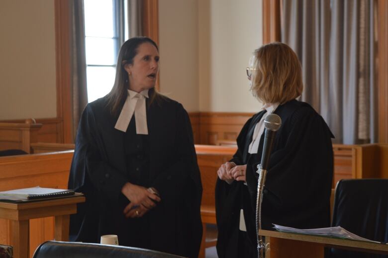 Two lawyers stand in a courtroom talking